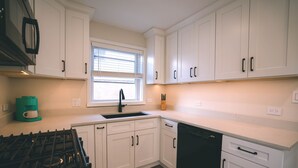 Una cucina moderna con mobili bianchi, un piano cottura nero e una lavastoviglie.