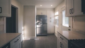 Una cucina moderna con mobili bianchi, un frigorifero in acciaio inossidabile e un piano cottura a gas.