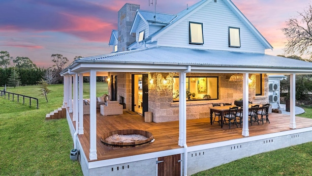 Een tweelaags huis met een overdekte patio, stenen open haard, buitenmeubels en een hottub.
