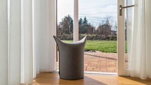 Una silla moderna en un umbral, con vista a un camino de ladrillo y árboles.