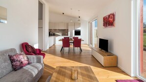 Una sala de estar moderna con sofá, mesa de centro, televisor y un comedor con sillas y mesa.