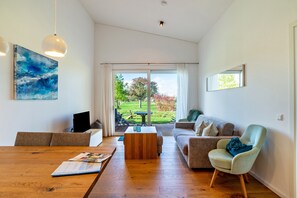Una sala de estar moderna con una mesa de centro de madera, un sofá, una silla y un cuadro en la pared.