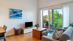 Een moderne woonkamer met een flatscreen televisie, een salontafel, een bank en een eethoek.