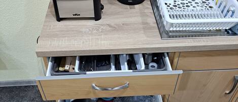 A kitchen with a toaster, coffee maker, and a basket of utensils on a wooden countertop.