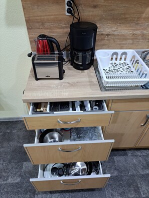 A kitchen with a toaster, coffee maker, and a basket of utensils on a wooden countertop.