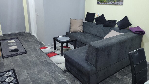 A living room with a grey sofa, a small black table, and a painting on the wall. - Holiday Apartment " In Elz" with Wi-Fi (Elz)