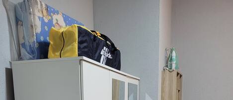 Une pièce comprenant une armoire, un lit, une étagère fixée au mur et un sol recouvert d’une moquette.