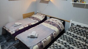 A twin room with two beds, a wall-mounted shelf with decorative items, and a painting. - Holiday Apartment " In Elz" with Wi-Fi (Elz)