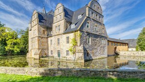 Un bâtiment historique en pierre, doté de plusieurs tours et entouré de douves.