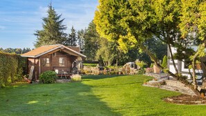 A wooden cabin with a sloped roof, a stone pathway, and a well-maintained lawn. - Holiday Home 'Ferienwohnung Im Grünen' with Shared Terrace and Wi-Fi (Bissendorf)