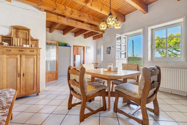 Un comedor con una mesa y sillas de madera, un armario y vistas por una ventana.