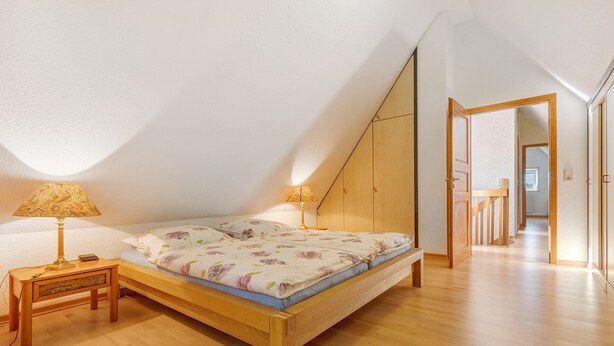 Une chambre avec un lit en bois, deux lampes de chevet et un plancher en bois.