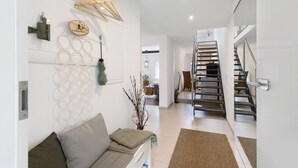 Un intérieur moderne avec un canapé, des porte-serviettes fixés au mur, un escalier et une porte.
