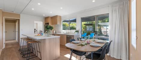 A modern kitchen with a central island, bar stools, and a dining area with a table set for four.