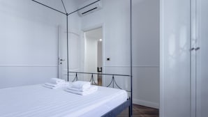 A neatly made bed with white linens and towels, a modern metal bed frame, and a white wardrobe with a mirror. - Italianway Comfort - Bodio 6 (Milan)