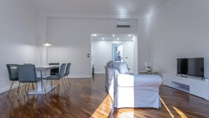 A modern living room with a sofa, a dining table with chairs, a TV, and a lamp. - Italianway Comfort - Bodio 6 (Milan)