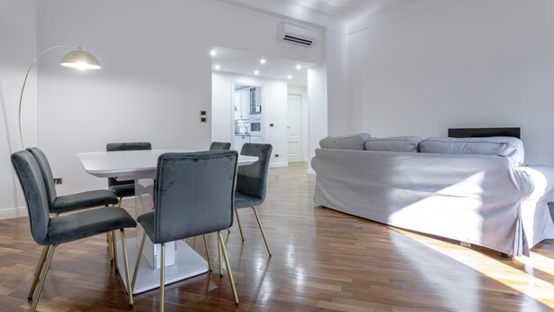 A modern living room with a dining area, a sofa, and a kitchen in the background. - Italianway Comfort - Bodio 6 (Milan)
