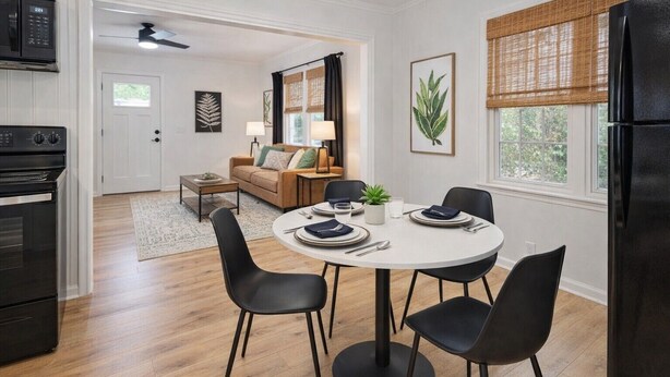 A modern kitchen with a dining area, featuring a round table with chairs, a black refrigerator, and a microwave.