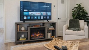 A modern living room with a fireplace, a flat-screen TV mounted above it, and a comfortable seating area with a sofa and a chair.