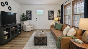 A living room with a TV, sofa, coffee table, and decorative items.