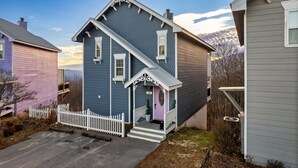 A two-story house with a porch, a white picket fence, and a number 102 sign.