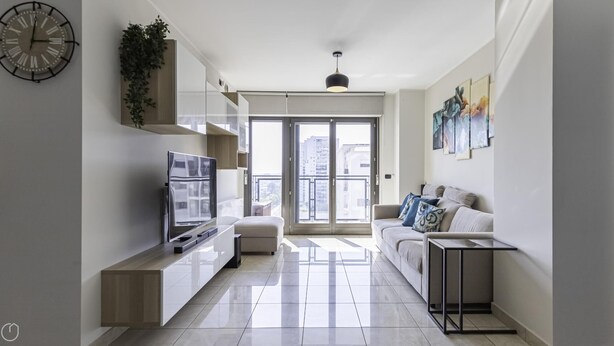 A modern living room with a flat-screen TV, a sofa, a coffee table, and a balcony with a city view. - Tognazzi 6 in Milan With 1 Bedrooms and 1 Bathrooms (Milan)