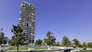 A modern high-rise building with multiple balconies, surrounded by a park with trees and benches. - Tognazzi 6 in Milan With 1 Bedrooms and 1 Bathrooms (Milan)