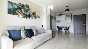 A modern living room with a sofa, a dining table with chairs, and a kitchen area with cabinets and a door. - Tognazzi 6 in Milan With 1 Bedrooms and 1 Bathrooms (Milan)