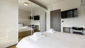 A modern hotel room with a large bed, a desk, a flat-screen TV mounted on the wall, and a wardrobe with mirrored doors. - Tognazzi 6 in Milan With 1 Bedrooms and 1 Bathrooms (Milan)