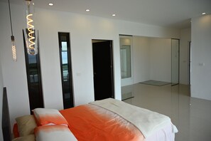 A modern bedroom with a bed, a hanging light fixture, and a large mirror.