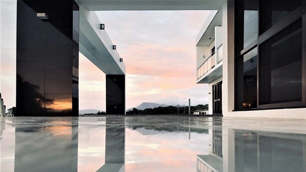 Ein modernes Gebäude mit einer spiegelnden Glasfläche, großen Fenstern und Blick auf den Sonnenuntergang.