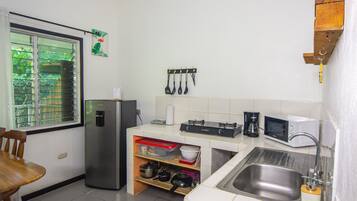 Una cocina compacta equipada con refrigerador, microondas, pileta y diferentes utensilios.