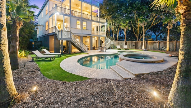 A two-story house with a swimming pool, outdoor furniture, and a well-maintained lawn.