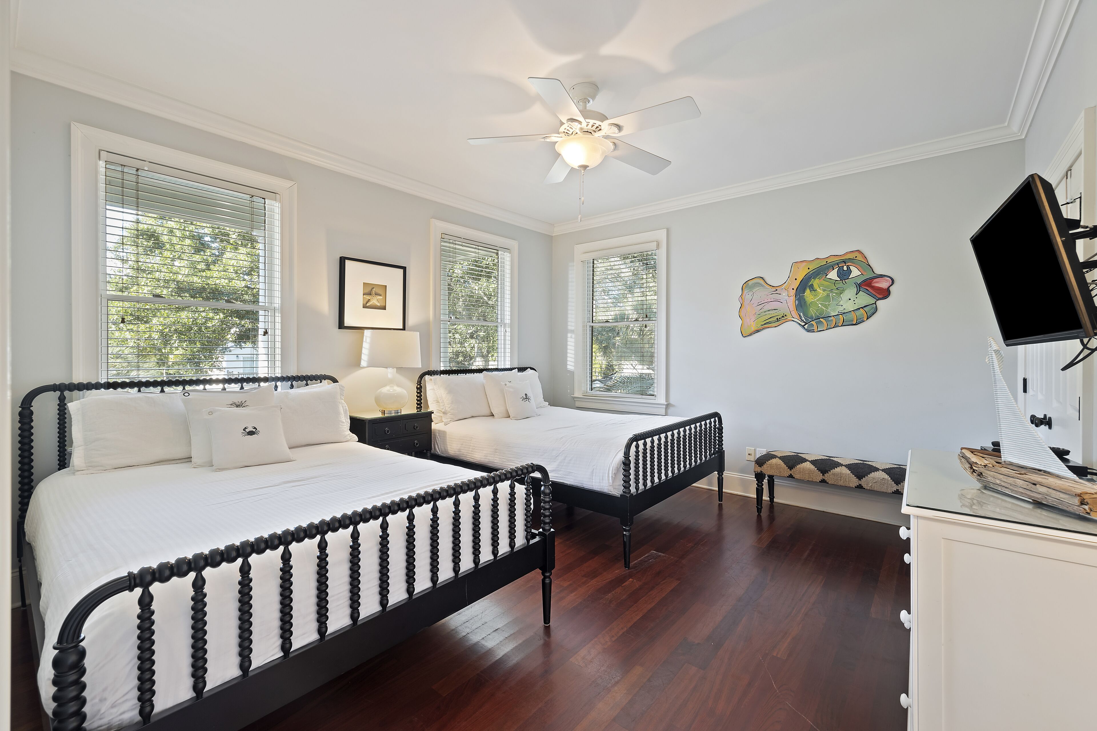 A bedroom with two beds, a ceiling fan, and a TV.