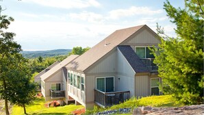 Une maison à deux étages, dotée d’un toit en pente, de grandes fenêtres et d’un balcon.