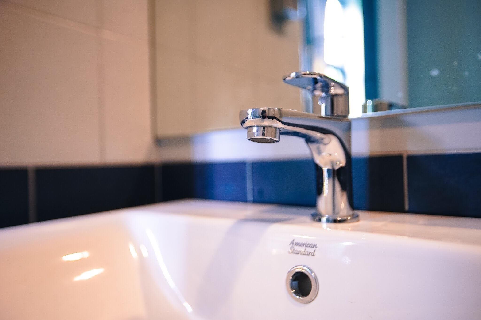 Un lavabo de salle de bain avec un robinet chromé et un miroir au-dessus.
