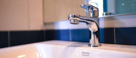 Un lavabo de salle de bain avec un robinet chromé et un miroir au-dessus.