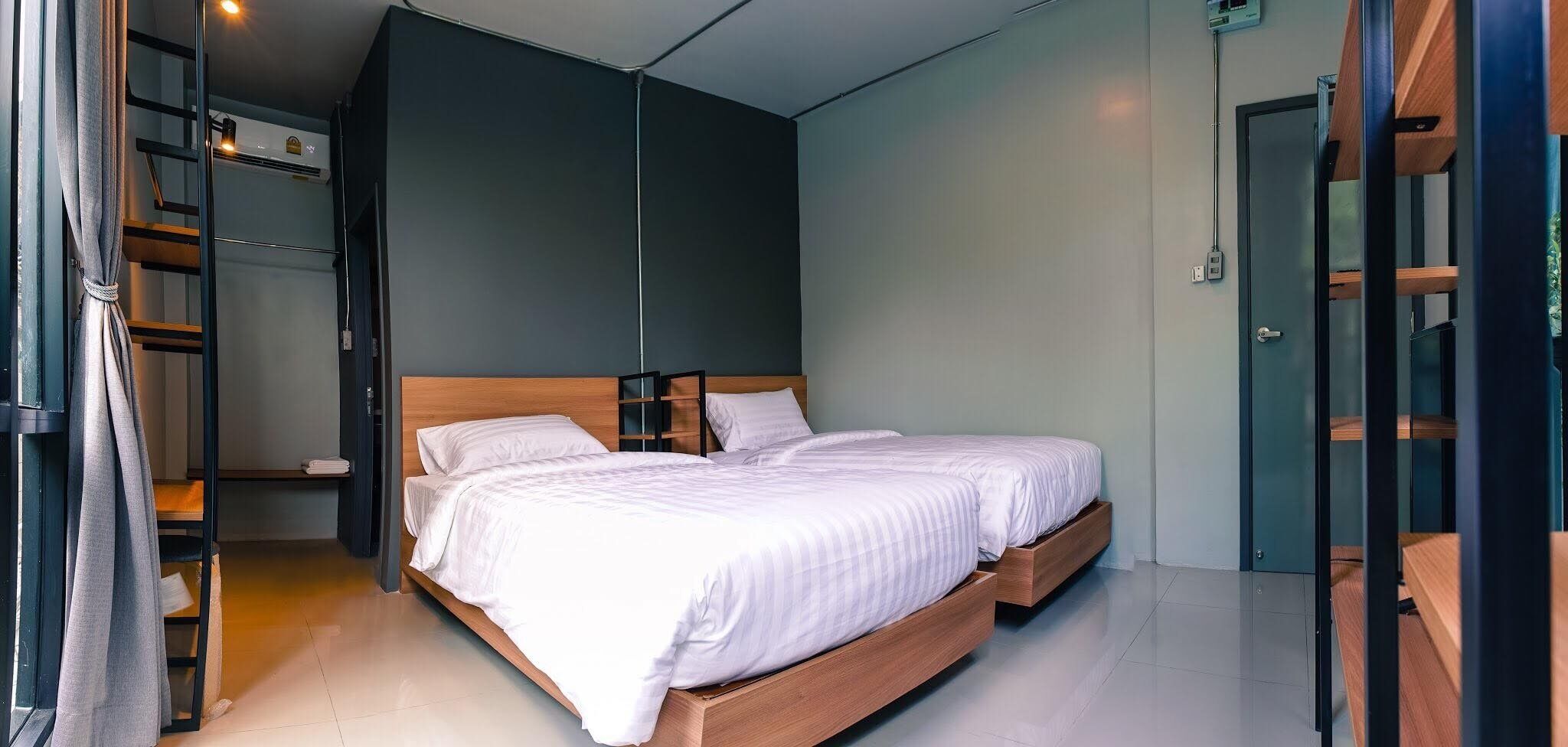 Un dormitorio moderno con cama de madera, armario empotrado y una pequeña zona de estar.