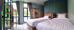 A modern bedroom with two beds, a built-in bench, and a large window with curtains. - Bed Garden 26 (Bangkok)