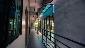 A corridor with large windows, a metal railing, and a ceiling with skylights. - Bed Garden 26 (Bangkok)