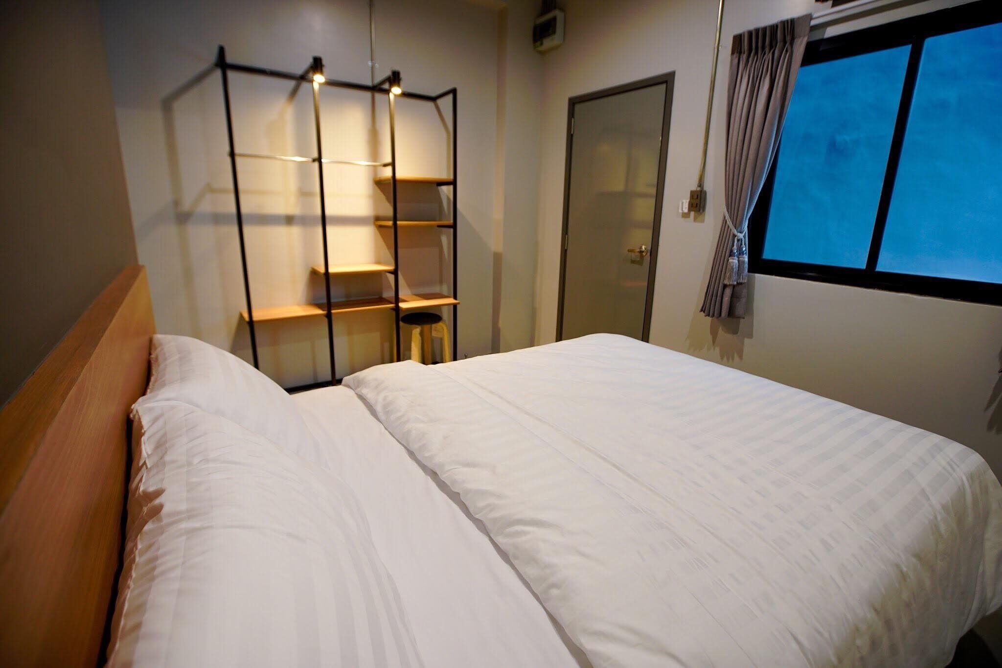 A bedroom with a bed, a wooden headboard, a wardrobe, and a window with curtains.
