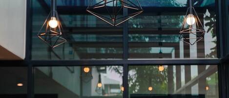 A modern interior with a glass wall, a wooden table, and three geometric pendant lights.