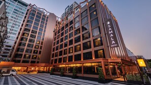Un hotel moderno con un evidente cartello con la scritta 'Samala Hotel', caratterizzato da un design contemporaneo, ampie finestre e un ingresso ben illuminato.