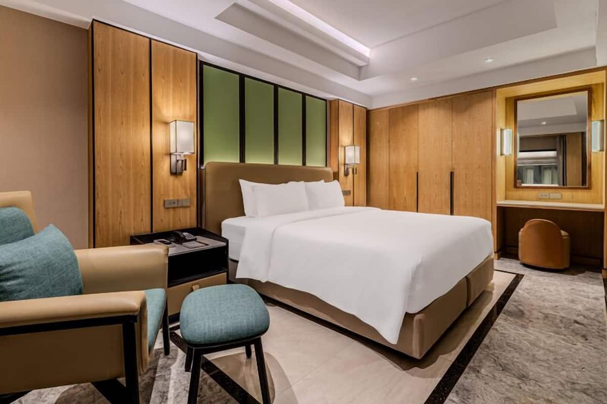 A hotel room with a large bed, a desk with a telephone, a chair, and a mirror.