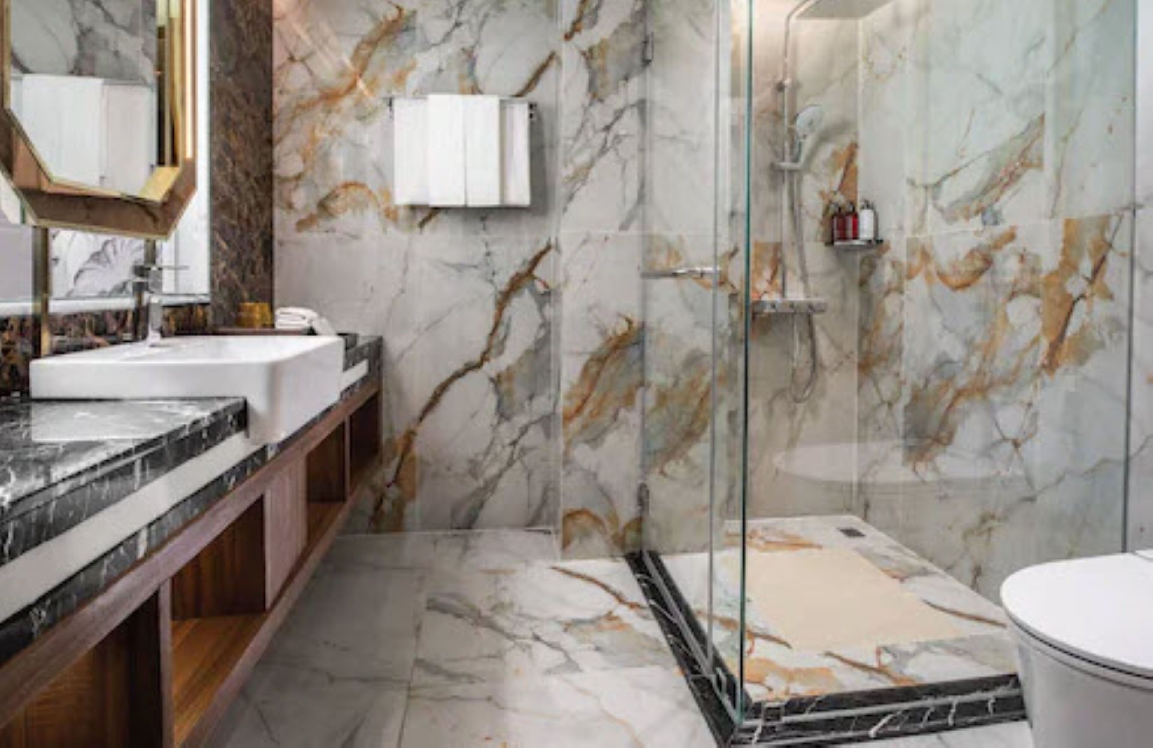 A bathroom with marble walls, a glass shower enclosure, and a wooden vanity.