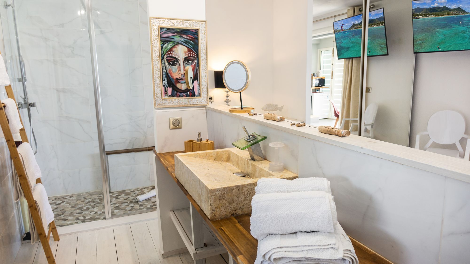 A modern bathroom with a glass shower, a marble sink, and a large mirror.