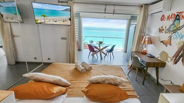 Habitació d'hotel amb llit, escriptori, cadira, televisió i balcó amb vista a l'oceà.