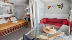 Un dormitori modern amb un llit de fusta, una taula de dinar de vidre i un sofà vermell.