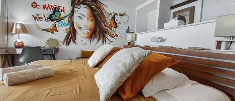 Ein Hotelzimmer mit Bett, Kissen, Schreibtisch, Lampe und Wandbild.