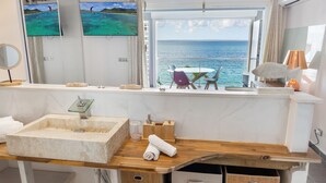Un bany modern amb un gran lavabo, un mirall i una finestra amb vista al mar.